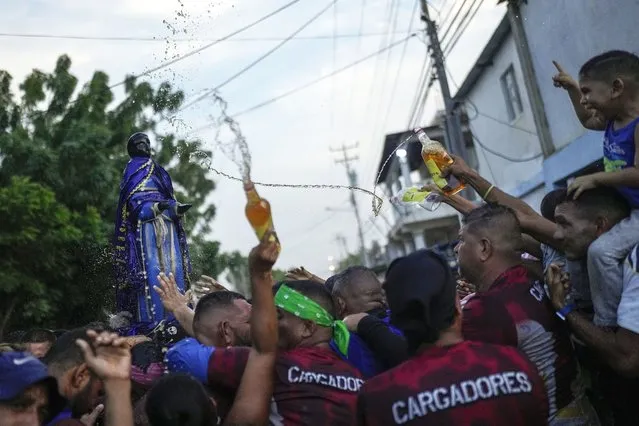 Devotees bathe a statue of San Benito de Palermo with rum during a procession honoring their patron saint, in Cabimas, Venezuela, December 27, 2023. (Photo by Matias Delacroix/AP Photo)