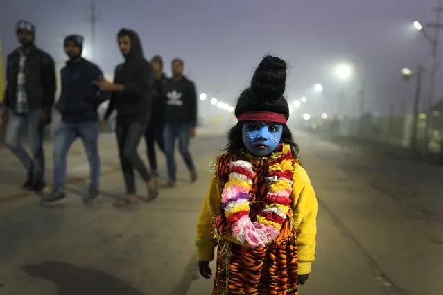 A child dressed as Hindu God Shiva begs for alms from devotees at the Sangam, the confluence of three rivers – the Ganges, the Yamuna and the mythical Saraswati, on the Makar Sankranti festival during the annual traditional fair of Magh Mela in Prayagraj, in the northern Indian state of Uttar Pradesh, Sunday, January 14, 2024. Hundreds of thousands of Hindu pilgrims are expected to take dips in the confluence, hoping to wash away sins during the month-long festival. (Photo by Rajesh Kumar Singh/AP Photo)