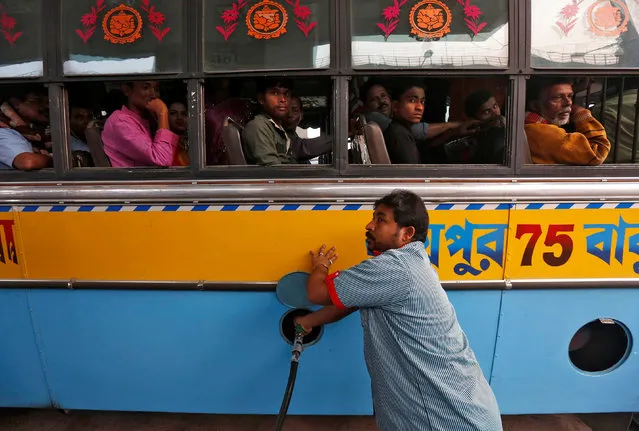 A worker fills a public bus with diesel as passengers look on, at a fuel station in Kolkata, India, February 1, 2017. (Photo by Rupak De Chowdhuri/Reuters)
