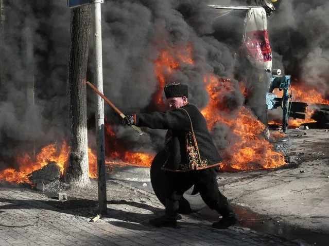 An anti-government protester threatens riot police outside Ukraine's parliament in Kiev. (Photo by Sergei Chuzavkov/AP Photo)