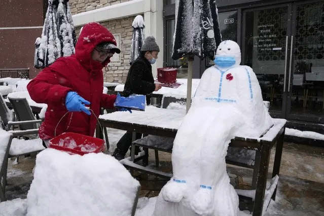 Workers at a restaurant build a snowman in the shape of a pandemic first responder with a protective suit and a mask in Beijing, China, Sunday, November 7, 2021. (Photo by Ng Han Guan/AP Photo)