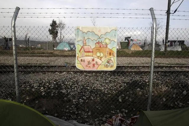 A baby blanket hangs to dry on the border fence at the Greek-Macedonian border, in a makeshift camp near the village of Idomeni, Greece, March 23, 2016. (Photo by Alexandros Avramidis/Reuters)