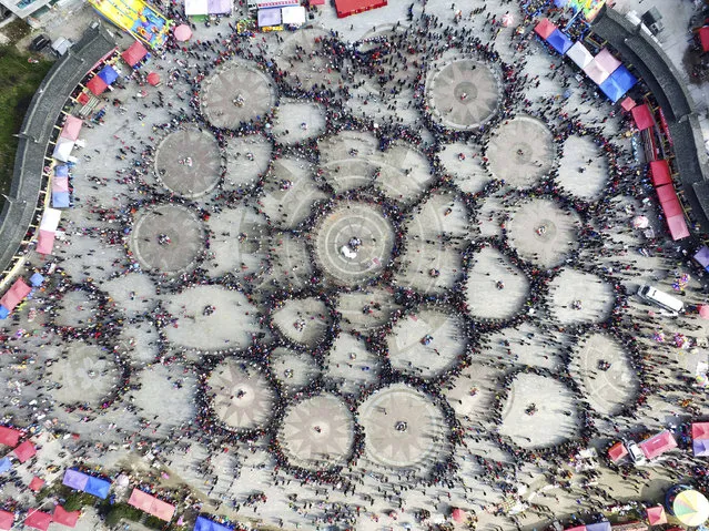 In this Thursday, February 16, 2017 photo, spectators watch as thousands of people of Miao ethnicity gather in circles to dance and play folk instruments known as lusheng at a public square in Zhouxi township in Kaili in southwestern China's Guizhou province. The Lusheng Festival is a key annual festival and gathering for members of China's Miao ethnic minority group. (Photo by Chinatopix via AP Photo)