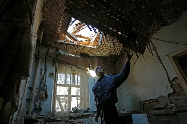 Local resident Evgeniy Lysak, 42, inspects his house, which locals said was damaged during recent shelling, on the outskirts of the rebel-controlled city of Donetsk, Ukraine on October 21, 2021. (Photo by Alexander Ermochenko/Reuters)