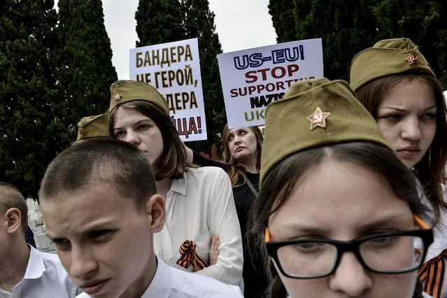 Russians living in Greece hold banners calling the E.U. and the U.S. to stop supporting the Ukrainian government, during an annual ceremony marking the end World War II, at an Allied Forces cemetery at the northern port city of Thessaloniki, Greece, on Saturday, May 9, 2015. Every year on this date Serbian and Russian veterans attend the ceremony and laid wreaths in commemoration of their compatriots who got killed during the war. (Photo by Giannis Papanikos/AP Photo)