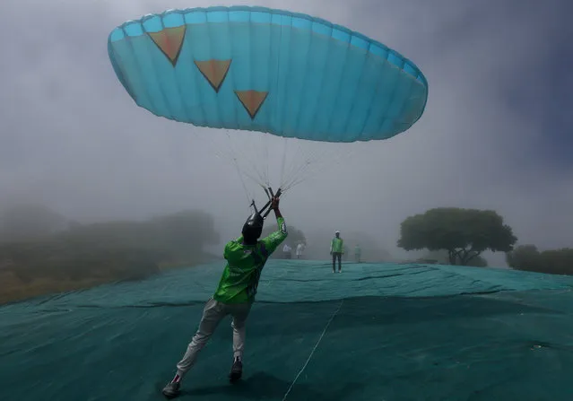 A person goes through the initial stages of paragliding during a misty morning of training on Signal Hill, in Cape Town, South Africa, on March 8, 2024. (Photo by Esa Alexander/Reuters)