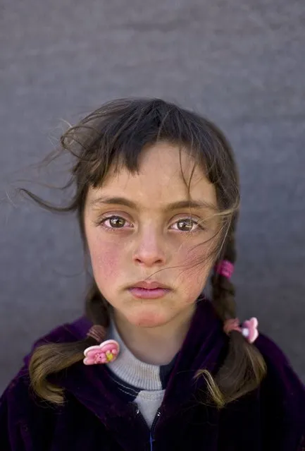 In this Friday, March 11, 2016 photo, Syrian refugee girl Zahra Mahmoud, 5, from Deir el-Zour, Syria, poses for a picture at an informal tented settlement near the Syrian border on the outskirts of Mafraq, Jordan. About half of the 4.8 million Syrians who fled their homeland are children, and some of the most vulnerable live in dozens of makeshift tent camps, including in Jordan, which has taken in close to 640,000 refugees. (Photo by Muhammed Muheisen/AP Photo)