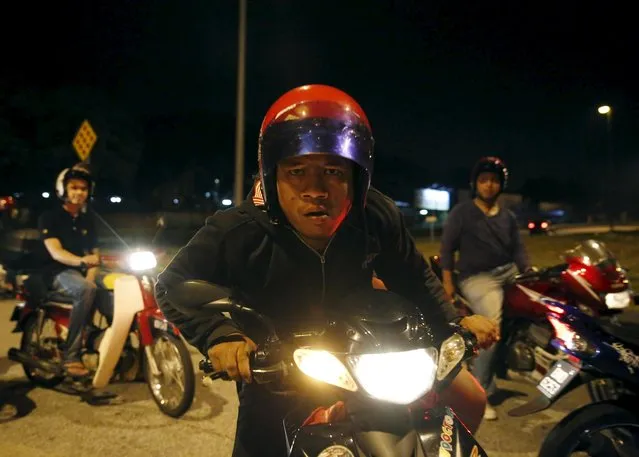 A motorcyclist looks into the camera on a highway in Kuala Lumpur, Malaysia, March 15, 2015. (Photo by Olivia Harris/Reuters)