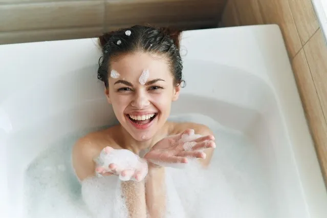 Young beautiful woman is lying in the bathroom with foam and playing with foam and bubbles. (Photo by ShotPrime/Getty Images)
