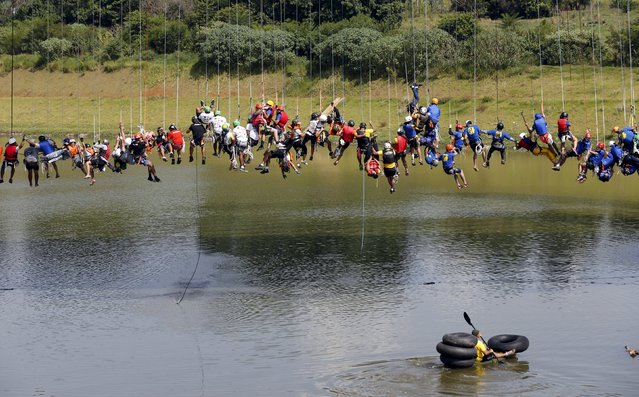 People balance on ropes after jumping off a bridge, which has a height of 30 meters, in Hortolandia, Brazil, April 10, 2016. (Photo by Paulo Whitaker/Reuters)