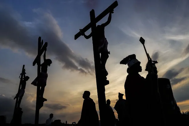 Penitents hang on crosses during a Way of the Cross reenactment, as part of Holy Week celebrations in the Petare neighborhood of Caracas, Venezuela, Friday, March 29, 2024. Holy Week commemorates the last week of the earthly life of Jesus Christ culminating in his crucifixion on Good Friday and his resurrection on Easter Sunday. (Photo by Matias Delacroix/AP Photo)