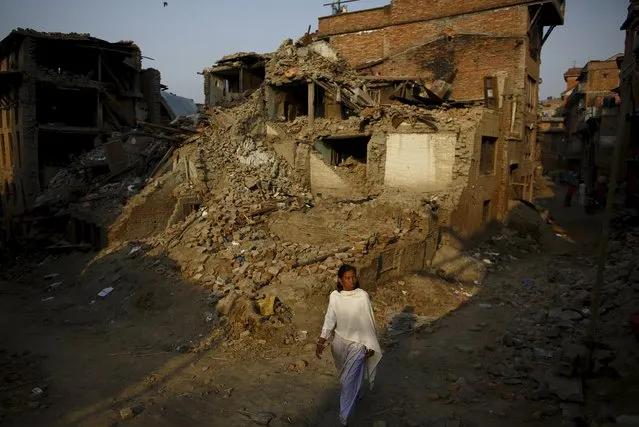 A woman walks along a street near collapsed houses, a month after the April 25 earthquake in Kathmandu, Nepal May 25, 2015. (Photo by Navesh Chitrakar/Reuters)