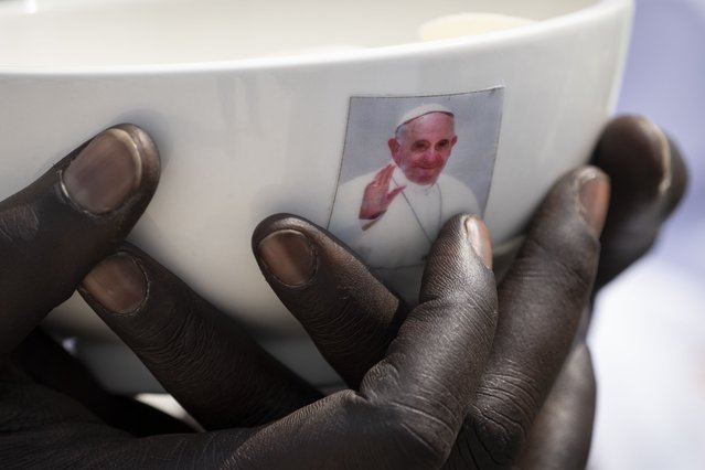 A priest holds a sacrament bowl showing a photograph of Pope Francis at a Holy Mass at the John Garang Mausoleum in Juba, South Sudan Sunday, February 5, 2023. Pope Francis is in South Sudan on the final day of a six-day trip that started in Congo, hoping to bring comfort and encouragement to two countries that have been riven by poverty, conflicts and what he calls a “colonialist mentality” that has exploited Africa for centuries. (Photo by Ben Curtis/AP Photo)