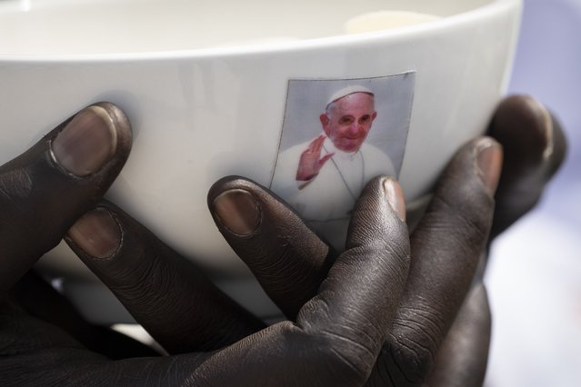 A priest holds a sacrament bowl showing a photograph of Pope Francis at a Holy Mass at the John Garang Mausoleum in Juba, South Sudan Sunday, February 5, 2023. Pope Francis is in South Sudan on the final day of a six-day trip that started in Congo, hoping to bring comfort and encouragement to two countries that have been riven by poverty, conflicts and what he calls a “colonialist mentality” that has exploited Africa for centuries. (Photo by Ben Curtis/AP Photo)