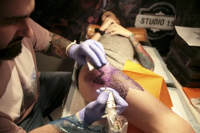 An artist works on a tattoo on a woman during the second International Tattoo Festival in Sochi, Russia, April 23, 2016. (Photo by Kazbek Basayev/Reuters)