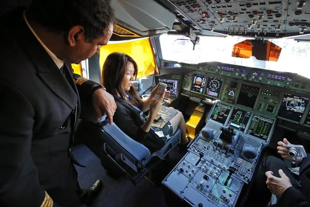 Visitors take photos during a press visit in the cockpit of the Airbus A380 of Qatar Airways presented at the Paris Air Show, in Le Bourget airport, north of Paris, Wednesday, June 17, 2015. Qatar Airways has brought 4 Airbus A380's in service since last year. (AP Photo/Francois Mori)