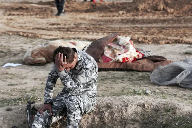 An Iraqi policeman collects himself as he is surrounded by bodies at the site of a mass grave containing some two dozen people, many of them children, in an area recently re-taken from Islamic State militants in Mosul, Iraq, Wednesday, March 15, 2017. (Photo by Christian Stephen/AP Photo)