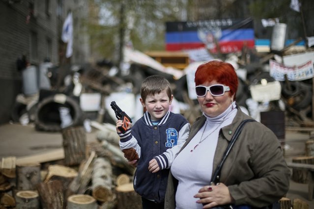 A boy with toy gun poses for picture in front of barricades at the police headquarters in the eastern Ukrainian town of Slaviansk, April 17, 2014. Russian President Vladimir Putin said on Thursday that Ukraine's government needs to provide guarantees to its Russian-speaking population in the east of the country to resolve the crisis. (Photo by Gleb Garanich/Reuters)