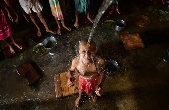 A young Nepali Hindu devotee takes a holy bath as he takes part in a ritual during the Janai Purnima Festival at the Pashupatinath Temple in Kathmandu on August 15, 2019. The Janai Purnima Festival is known as the Sacred Thread Festival during which Hindu men, especially the Brahmans and Chettris, perform their annual changing of Janai, a yellow cotton string worn across the chest or tied around the wrist of the right hand. (Photo by Prakash Mathema/AFP Photo)