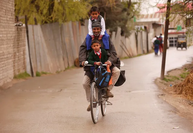 A man carries schoolchildren on his bicycle on a road in Srinagar, March 28, 2017. (Photo by Danish Ismail/Reuters)
