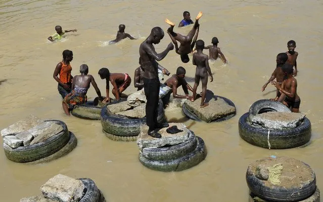 Ivorians bathe in a polluted body of water that flows through the Ebrie Lagoon in Abidjan on April 19, 2014. The level of pollution in the lagoon has increased in recent years due to the discharge of sewage from nearby urban areas. (Photo by Sia Kambou/AFP Photo)