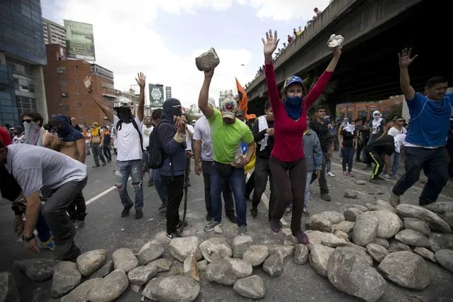 Demonstrators make a roadblock during a protest in Caracas, Venezuela, Thursday, April 6, 2017. The South American country has seen near-daily protests since the Supreme Court issued a ruling nullifying congress last week. The court pulled that decision back after it came under heavy criticism, but opposition leaders said the attempt to invalidate a branch of power revealed the administration's true dictatorial nature. (Photo by Ariana Cubillos/AP Photo)