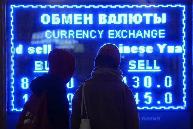 Women look at a screen displaying exchange rate at a currency exchange office in St. Petersburg, Russia, Tuesday, March 1, 2022. The Russian currency plunged about 30% against the U.S. dollar Monday after Western nations announced moves to block some Russian banks from the SWIFT international payment system and to restrict Russia's use of its massive foreign currency reserves. (Photo by Dmitri Lovetsky/AP Photo)