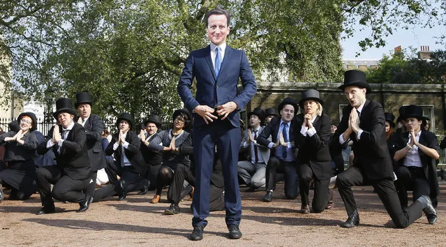 “Artful Tax Dodgers” flash mob including a protestor wearing a mask of Britain's Prime Minister David Cameron sing and dance at the entrance to Lancaster House, where the Anti-Corruption summit is taking place in London, Thursday, May 12, 2016. The flash mob protest took place to highlight a petition organised by campaign group 38 Degrees, and signed by 200,000 people calling on David Cameron to shut down British owned tax havens. (Photo by Kirsty Wigglesworth/AP Photo)
