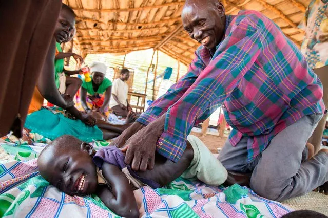 A refugee child from Sudan with disabilities is massaged at Doro refugee camp, in Maban, near Bunj, South Sudan, on May 3, 2017. Massagers from the local community, trained by the NGO Jesuit Refugee Service, provide massages to disabled refugee children three times a week to reduce their stress in the camp and improve their mobility. (Photo by Albert Gonzalez Farran/AFP Photo)