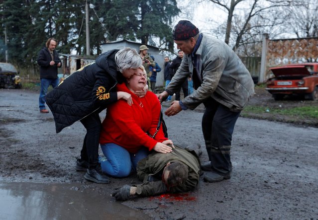 A woman mourns over the body of her relative Alexander, who was killed at his workplace in a car repair shop during a recent shelling in the course of Russia-Ukraine conflict, in Donetsk, Russian-controlled Ukraine on April 7, 2023. (Photo by Alexander Ermochenko/Reuters)