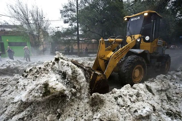A bulldozer removes the hail in a street after a hailstorm in the Aclimacao neighborhood in Sao Paulo, Brazil on May 19, 2014. After the severe overnight hailstorm a layer of hailstones as deep as 20 centimeters covered streets and parks, drawing people to make snowmen and play in the ice, an unusual scene to the city. (Photo by Nelson Almeida/AFP Photo)