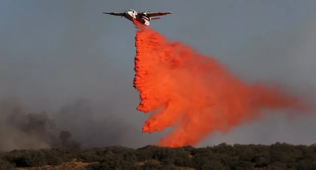 Air tankers make drops at the North Fire near the Phelan, California July 17, 2015. A fast-moving brush fire in the Southern California foothills overran a packed freeway in a mountain pass on Friday, destroying four structures and torching 20 vehicles as drivers abandoned their cars and scrambled to safety. (Photo by Gene Blevins/Reuters)