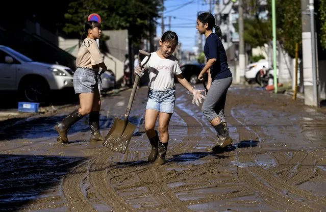 Children clear mud from a street after floodwaters receded in the aftermath of Typhoon Hagibis, in Kawasaki on October 13, 2019. Japan's military scrambled October 13 to rescue people trapped by flooding after powerful Typhoon Hagibis ripped across the country, killing at least 11 people and leaving more than a dozen missing. (Photo by William West/AFP Photo)
