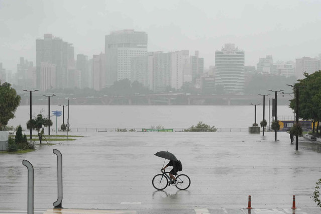 A man rides a bicycle amid heavy rains at a public park along the Han River in Seoul, South Korea, Thursday, July 18, 2024. (Photo by Ahn Young-joon/AP Photo)