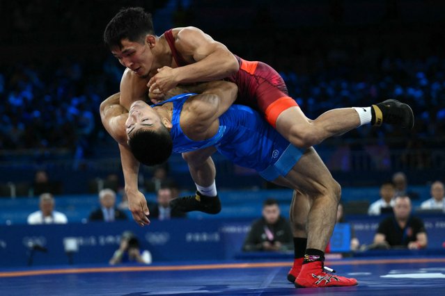 Kyrgyzstan's Zholaman Sharshenbekov (red) wrestles Japan's Kenichiro Fumita (blue) in their men's greco-roman 60kg wrestling semi-final match at the Champ-de-Mars Arena during the Paris 2024 Olympic Games, in Paris on August 5, 2024. (Photo by Luis Robayo/AFP Photo)