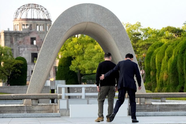 Japan's Prime Minister Fumio Kishida (R) escorts Ukraine's President Volodymyr Zelensky closer to the Cenotaph for the Victims of the Atomic Bomb during a wreath laying ceremony at the Hiroshima Peace Memorial Park, following the G7 Leaders' Summit in Hiroshima on May 21, 2023. (Photo by Eugene Hoshiko/Pool via AFP Photo)