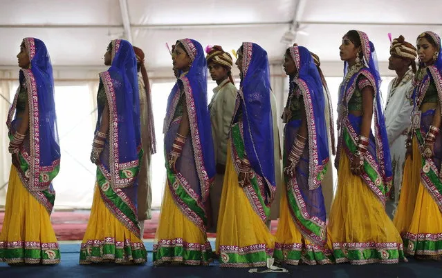 Brides and grooms stand in queue to enter the venue of a mass wedding ceremony at Ramlila ground in New Delhi June 15, 2014. A total of 92 physically challenged couples of all religions from across India took their wedding vows on Sunday during the mass wedding ceremony organised by a non-governmental organisation (NGO), organisers said. (Photo by Adnan Abidi/Reuters)