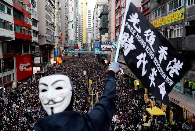 A protester wearing a Guy Fawkes mask waves a flag during a Human Rights Day march, organised by the Civil Human Right Front, in Hong Kong, China on December 8, 2019. (Photo by Danish Siddiqui/Reuters)