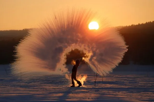 Winter outdoor sports enthusiast Olesya Ushakova poses while throwing hot water into subzero air as she participates in the “Dubak Challenge”, an intense cold challenge that is popular on social media in Russia, during sunset outside the Siberian city of Krasnoyarsk, Russia February 8, 2019. (Photo by Ilya Naymushin/Reuters)