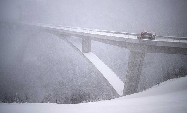 A snow removal vehicle drives on the Tamina bridge in Valens, Switzerland, Sunday, January 9, 2022. On the northern side of the Alps, up to 50 centimetres of snow are expected to fall today at higher altitudes. (Photo by Gian Ehrenzeller/Keystone via AP Photo)