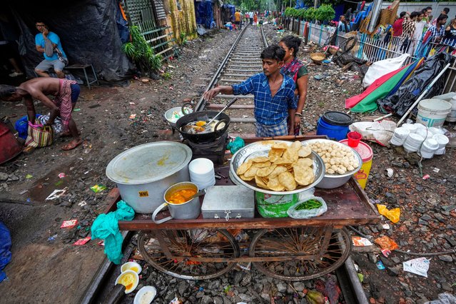 A vendor prepares breakfast on his mobile cart place on a railway track on which train services are suspended temporarily due to festival rush in Kolkata, India, Wednesday, October 2, 2024. (Photo by Bikas Das/AP Photo)