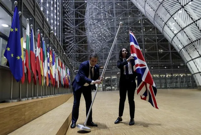 Officials remove the British flag at European Union Council in Brussels, Belgium on January 31, 2020. (Photo by Olivier Hoslet/Pool via Reuters)