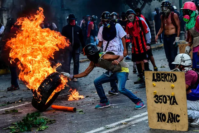 Opposition demonstrators burn a tire during an anti- government protest in Caracas, on July 26, 2017. Venezuelans blocked off deserted streets Wednesday as a 48- hour opposition- led general strike aimed at thwarting embattled President Nicolas Maduro' s controversial plans to rewrite the country' s constitution got underway. (Photo by Ronaldo Schemidt/AFP Photo)