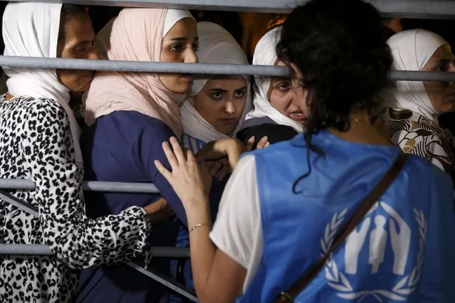 Syrian refugees listen to a United Nations High Commissioner for Refugees (UNHCR) volunteer before boarding the passenger ship “Eleftherios Venizelos” at the port on the Greek island of Kos, August 15, 2015. The vessel will house more than 2500 refugees and migrants who entered the country from theTurkish coast and will be used as a registration center for migrants. (Photo by Alkis Konstantinidis/Reuters)