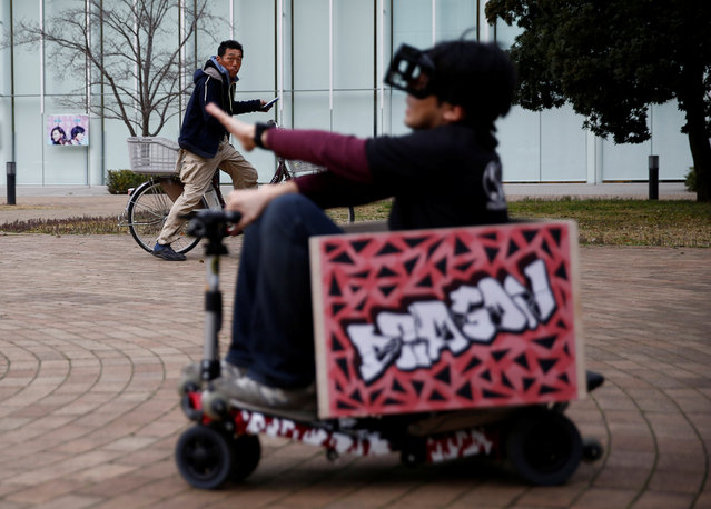 A passer-by looks at a “Hado Kart” player during the sport's demonstration, in Tokyo, Japan, March 18, 2017. In “HADO Kart”, players in head-mounted augmented-reality displays and armband sensors dodge waves of light as they fire energy balls at each other by moving around with riding a Kart in a virtual arena. (Photo by Kim Kyung-Hoon/Reuters)
