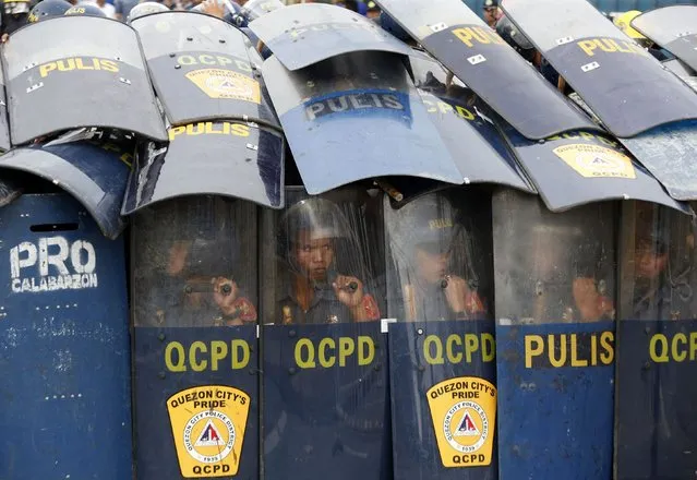 Police take up positions behind anti-riot shields as protesters try to remove a police barricade while Philippine President Benigno Aquino delivers his fifth State of the Nation Address (SONA) during the joint session of the 16th Congress at the House of Representatives of the Philippines in Quezon city, Metro Manila July 28, 2014. (Photo by Erik De Castro/Reuters)