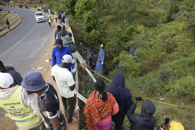 People look at the wreckage of a bus that plunged into Nithi bridge on Sunday, in Tharaka Nithi county Meru, Kenya, Monday, July 25, 2022. Police in Kenya say at least 21 people have died after a bus fell off a bridge and plunged into a river along the highway from the capital, Nairobi, to the central town of Meru. One senior policeman said the bus, traveling from Meru, “must have developed brake failure because it was at a very high speed” when the crash occurred. (Photo by Dennis Dibondo/AP Photo)