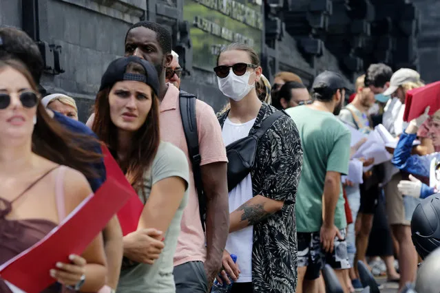 In this March 23, 2020 photo, foreign tourists who are unable to fly home due to the new coronavirus outbreak, queue up outside an immigration office to extend their visas in Bali, Indonesia. Tourists across Asia are finding their dream vacations have turned into travel nightmares as airlines cancel flights and countries close their borders in the fight against the coronavirus pandemic. (Photo by Firdia Lisnawati/AP Photo)