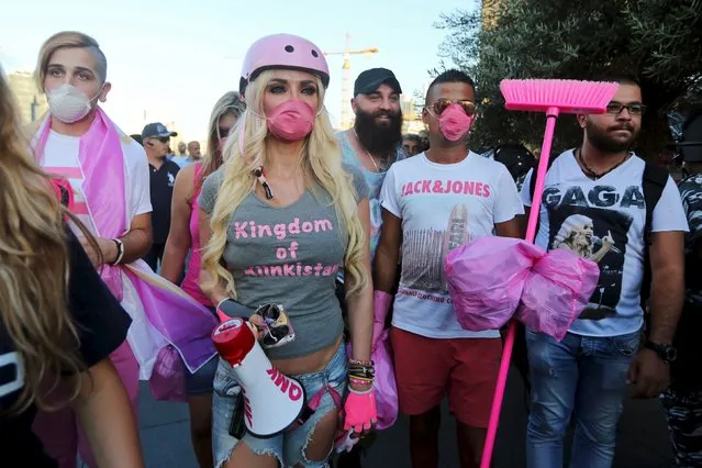 Lebanese Pop star Myriam Klink (in pink helmet) and her fans wear masks as they take part in an anti-government protest at Martyrs' Square in downtown Beirut, Lebanon August 29, 2015. Thousands of protesters waving Lebanese flags and chanting anti-government slogans converged on a square in central Beirut on Saturday for a rally against political leaders they say are incompetent and corrupt.(Photo by Hasan Shaaban/Reuters)