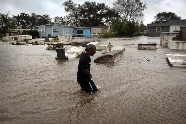 Errol Ragas walks past the flooded cemetery in Plaquemines Parish as he heads back to his home to recover dry blankets on Aug. 29. (Photo by John Moore)